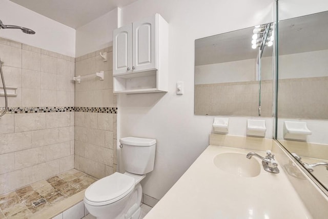 bathroom featuring vanity, toilet, and tiled shower