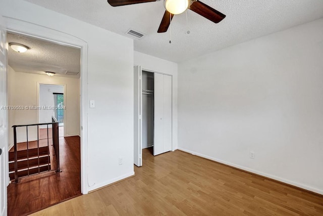 unfurnished bedroom featuring hardwood / wood-style floors, a textured ceiling, a closet, and ceiling fan