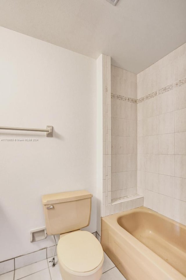 bathroom featuring tile patterned floors, tiled shower / bath combo, and toilet