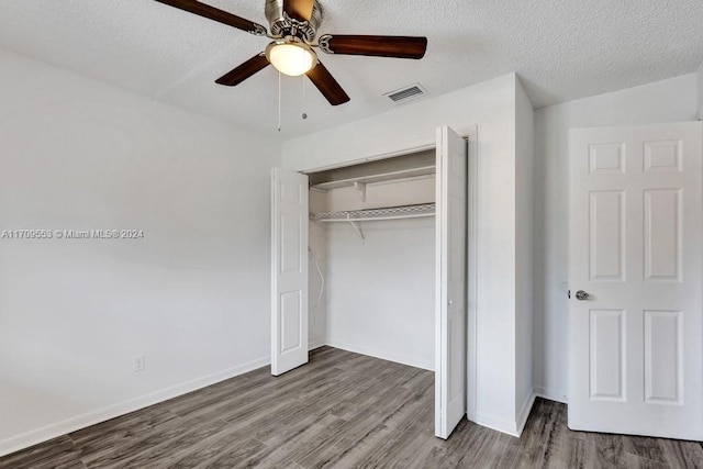 unfurnished bedroom with a textured ceiling, a closet, hardwood / wood-style flooring, and ceiling fan