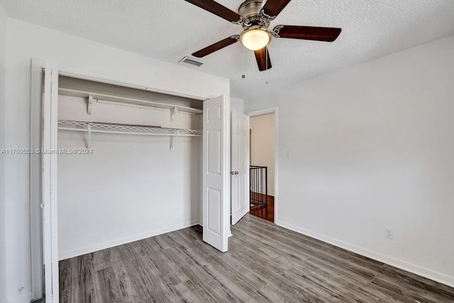 unfurnished bedroom with hardwood / wood-style floors, a textured ceiling, a closet, and ceiling fan