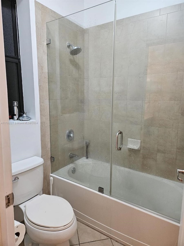 bathroom with tile patterned flooring, toilet, and shower / bath combination with glass door