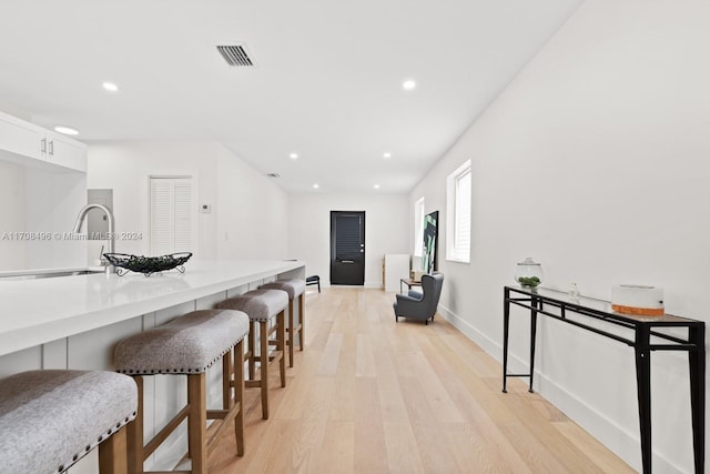 kitchen featuring a kitchen bar, light wood-type flooring, white cabinetry, and sink