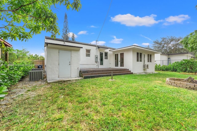 rear view of house featuring french doors, cooling unit, and a lawn