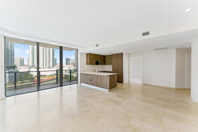 interior space with expansive windows, sink, and an island with sink