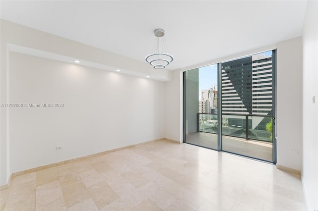 empty room featuring expansive windows and a notable chandelier