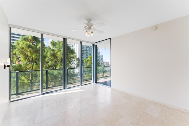 unfurnished room with ceiling fan and a wall of windows