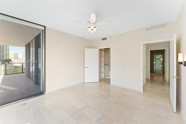 unfurnished bedroom with ceiling fan, a spacious closet, and a closet