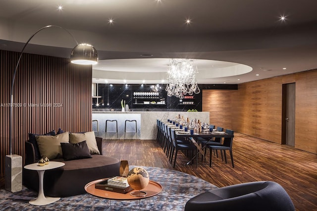 interior space with wood-type flooring, bar, a notable chandelier, and wood walls