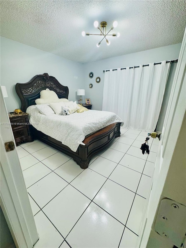 bedroom featuring a chandelier, a textured ceiling, and tile patterned floors