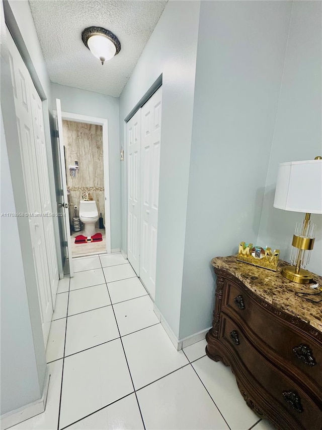 hallway featuring light tile patterned floors and a textured ceiling