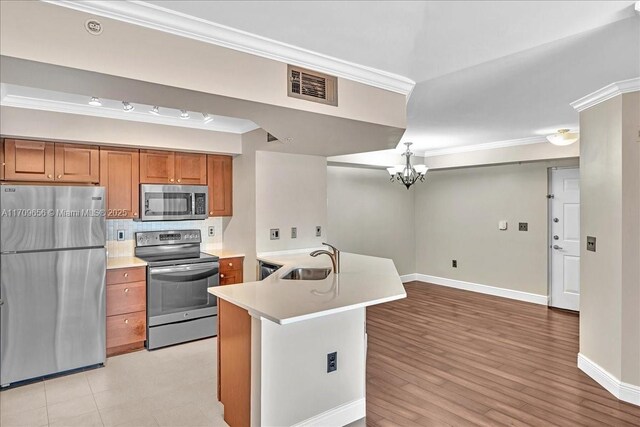 kitchen featuring sink, stainless steel appliances, a chandelier, light hardwood / wood-style floors, and ornamental molding