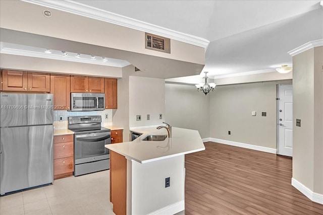 kitchen with sink, an inviting chandelier, stainless steel appliances, tasteful backsplash, and ornamental molding