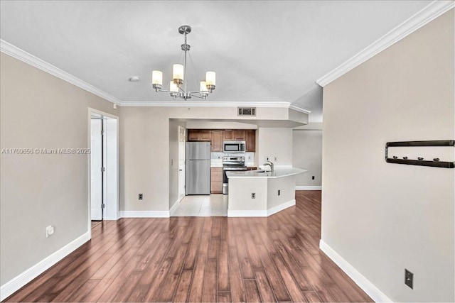 kitchen featuring crown molding, decorative light fixtures, stainless steel appliances, and hardwood / wood-style flooring