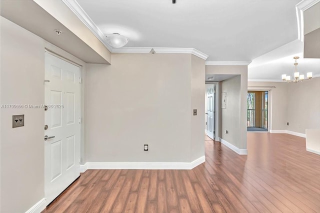 spare room with hardwood / wood-style flooring, ornamental molding, and a chandelier