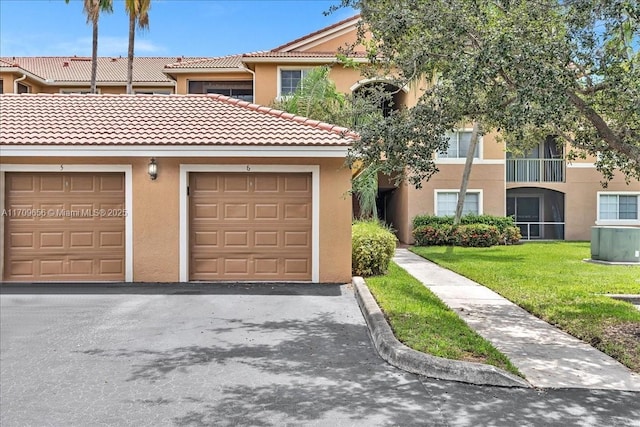 3659 NW Adriatic Ln Unit 305, Jensen Beach, FL 34957 - view of property featuring stucco siding, a front yard, driveway, an attached garage, and a tile roof