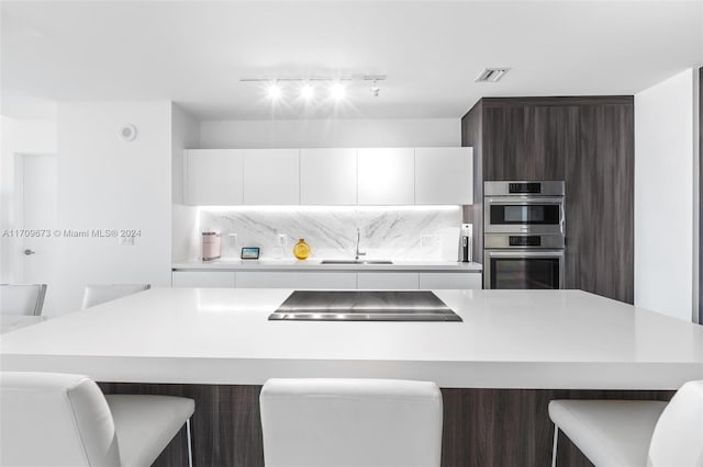 kitchen with a kitchen breakfast bar, white cabinetry, a kitchen island, and double oven