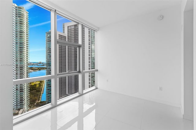 tiled empty room featuring floor to ceiling windows and a water view