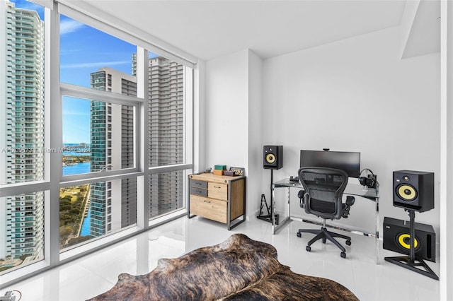 tiled office space featuring a water view, a wall of windows, and a healthy amount of sunlight