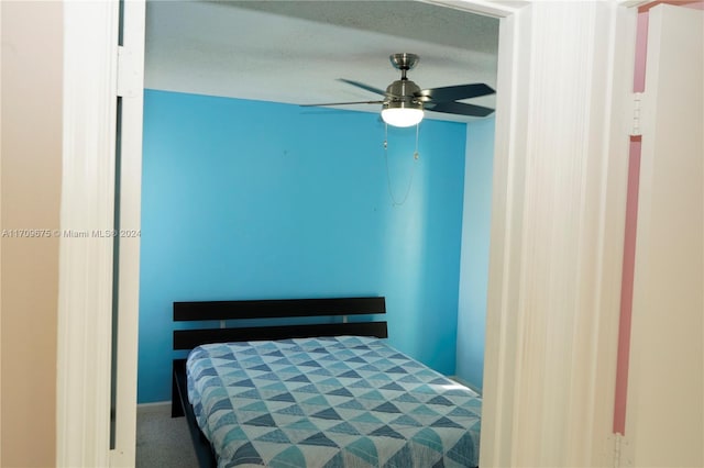 bedroom with ceiling fan, carpet floors, and a textured ceiling