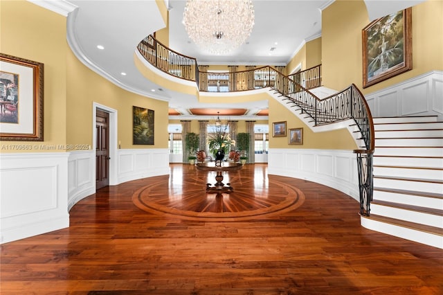 foyer with french doors, hardwood / wood-style flooring, ornamental molding, a towering ceiling, and a chandelier