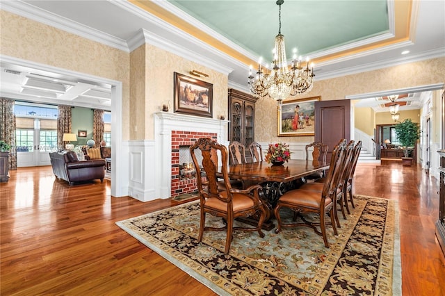 dining area featuring hardwood / wood-style floors, french doors, ornamental molding, a fireplace, and a notable chandelier