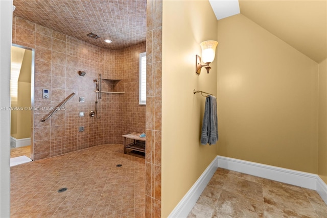 bathroom with a tile shower and lofted ceiling