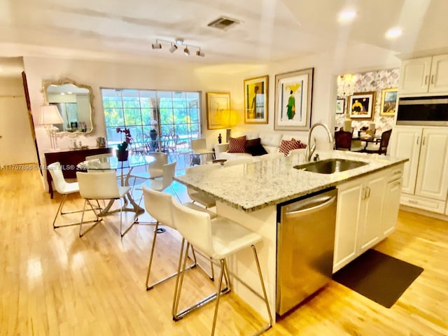 kitchen featuring sink, stainless steel dishwasher, an island with sink, a breakfast bar area, and white cabinets