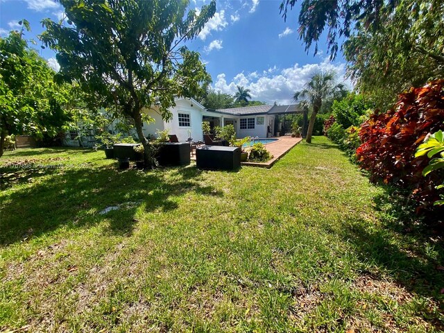 7521 SW 165th Ter, Palmetto Bay, FL 33157 - view of grassy yard featuring an outdoor pool, glass enclosure, a patio, and an outdoor hangout area
