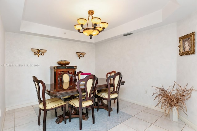 tiled dining space with a tray ceiling and a notable chandelier