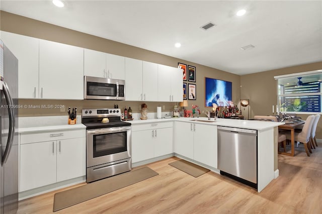 kitchen featuring white cabinets, light hardwood / wood-style floors, kitchen peninsula, and stainless steel appliances