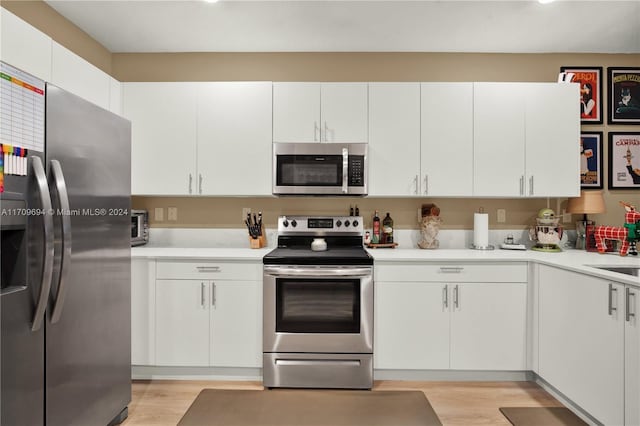 kitchen featuring sink, stainless steel appliances, white cabinetry, and light hardwood / wood-style flooring