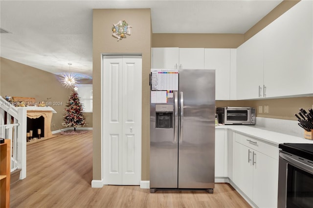 kitchen featuring white cabinets, vaulted ceiling, appliances with stainless steel finishes, and light hardwood / wood-style flooring