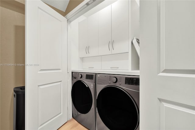 clothes washing area with light hardwood / wood-style floors, cabinets, and independent washer and dryer