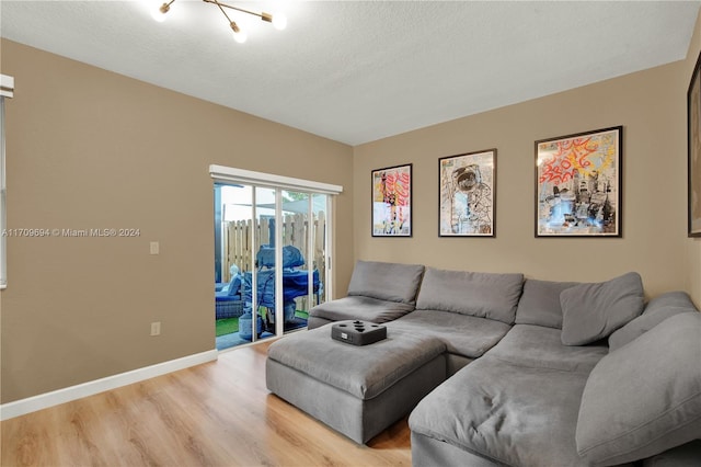 living room featuring a chandelier, a textured ceiling, and light hardwood / wood-style flooring