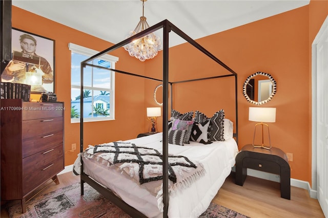 bedroom with hardwood / wood-style flooring and an inviting chandelier