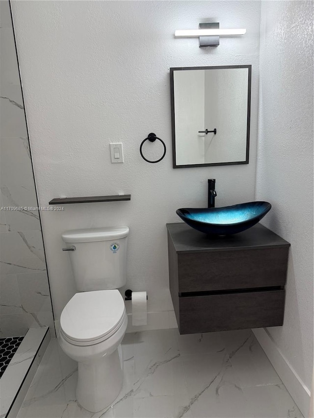 bathroom with a tile shower, vanity, and toilet