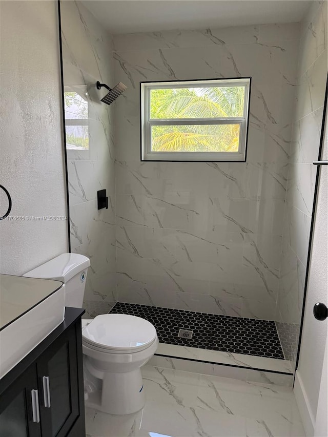 bathroom featuring vanity, toilet, and a tile shower