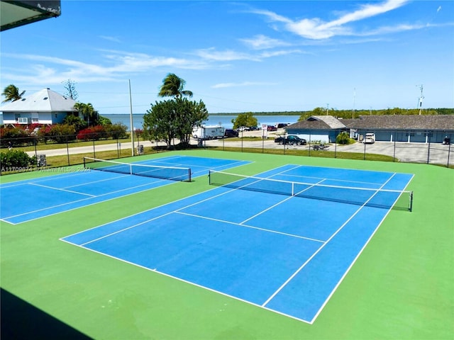 view of tennis court featuring basketball hoop and a water view