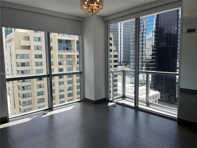 tiled spare room featuring a chandelier and floor to ceiling windows