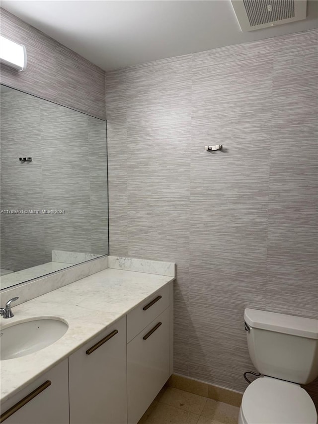 bathroom featuring vanity, toilet, and tile walls