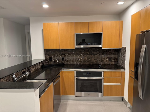 kitchen with decorative backsplash, appliances with stainless steel finishes, sink, and dark stone countertops