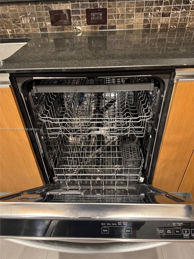 room details with backsplash, dark stone countertops, and dishwashing machine