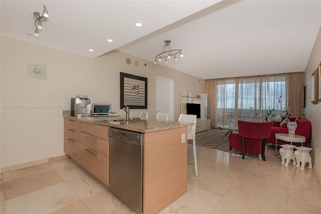 kitchen with light brown cabinets, a kitchen breakfast bar, sink, stainless steel dishwasher, and light stone countertops