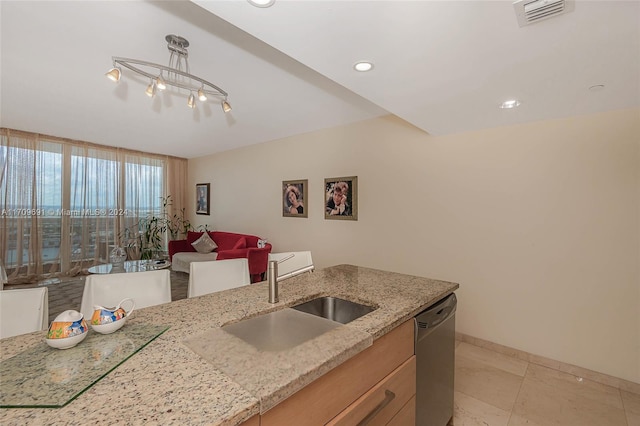 kitchen featuring light stone countertops, sink, hanging light fixtures, stainless steel dishwasher, and light tile patterned floors