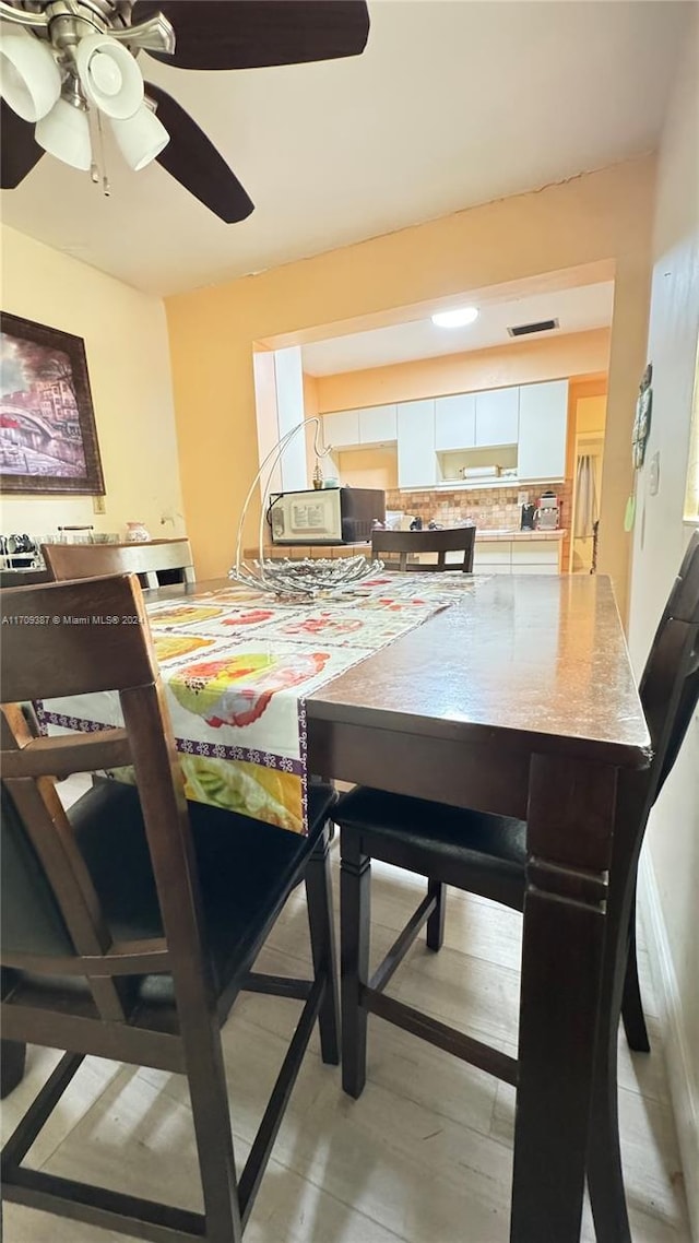 dining space featuring light wood-type flooring and ceiling fan