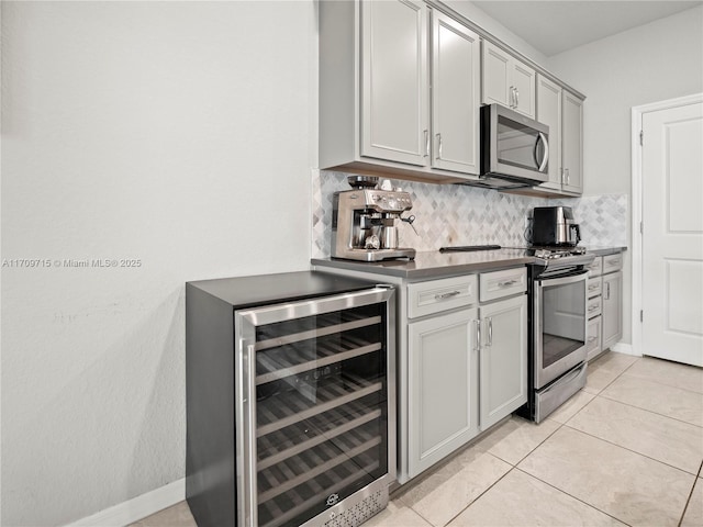 kitchen featuring appliances with stainless steel finishes, tasteful backsplash, wine cooler, gray cabinets, and light tile patterned floors