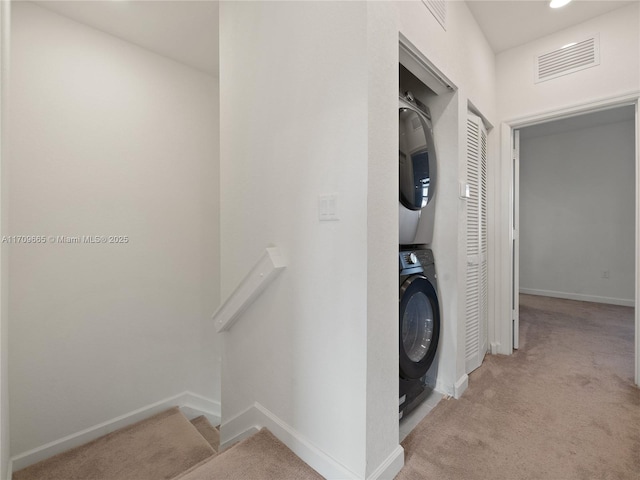 corridor featuring light colored carpet and stacked washer / drying machine