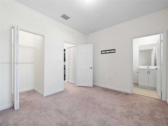 unfurnished bedroom featuring sink, a spacious closet, light carpet, and connected bathroom