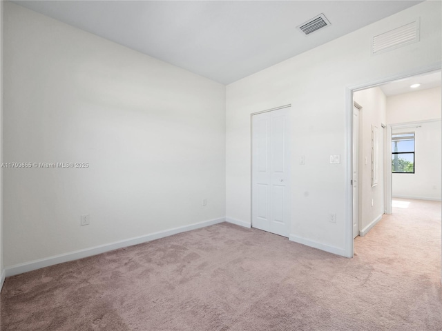 unfurnished bedroom with light colored carpet and a closet